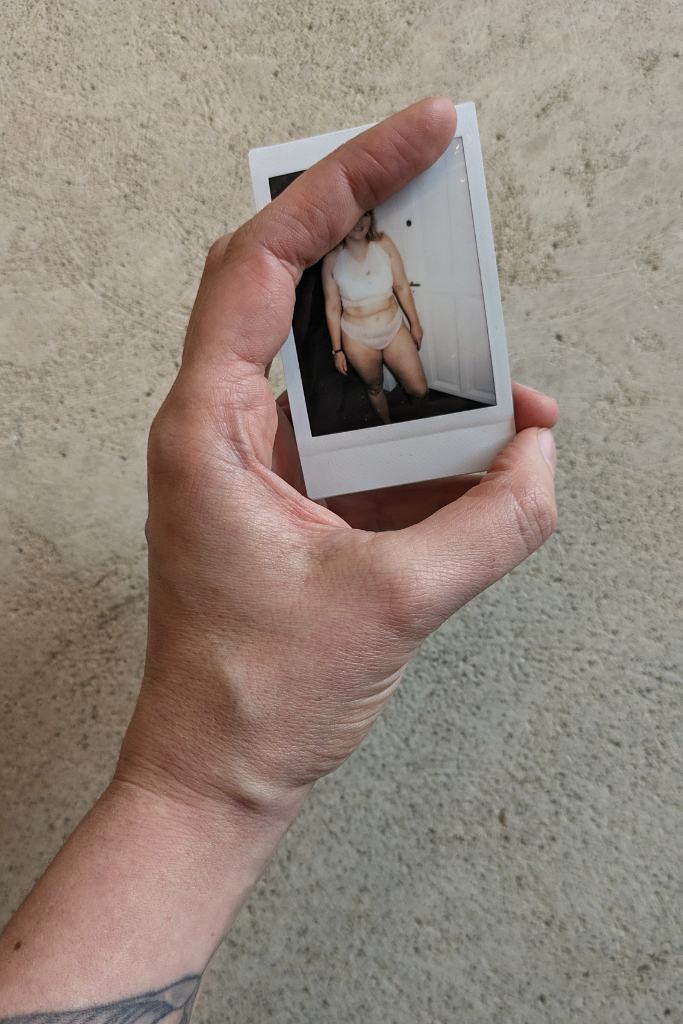 Zippora zeigt ein Polaroid Foto von Bralette zum Hochzeitskleid.