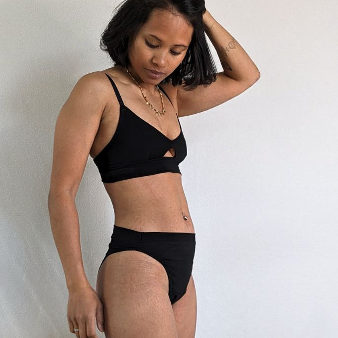 Le mannequin pose de côté face à l'objectif avec l'ensemble Thea en Tencel Lyocell