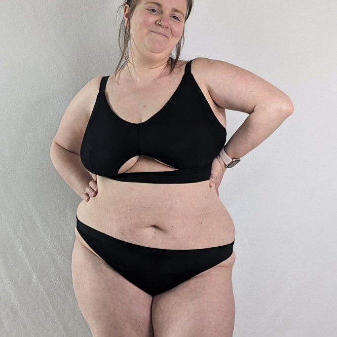 Le modèle porte le Bralette Thea avec un beau cut out devant en noir.
