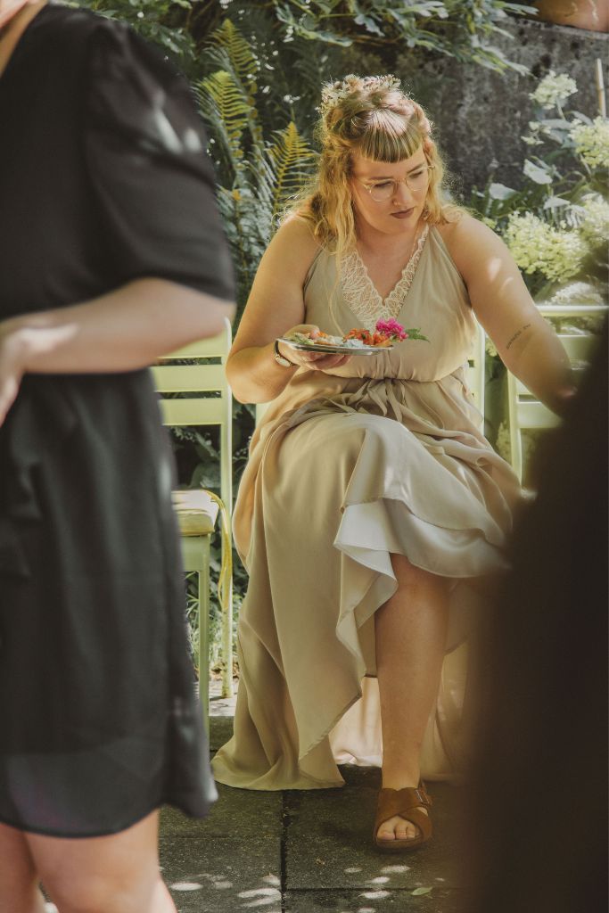 Braut mit passendem Bralette sitzt auf Stuhl und geniesst das Apéro.