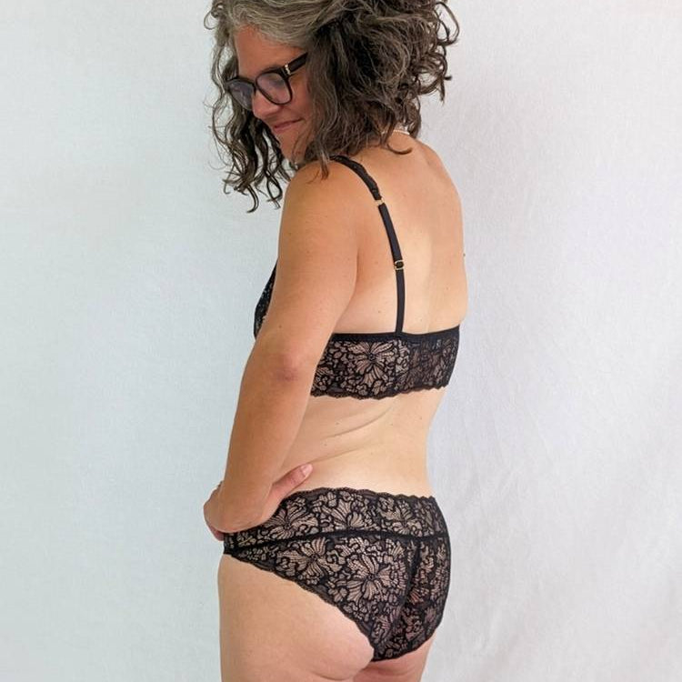 Une personne en lingerie noire en dentelle regarde par-dessus son épaule.