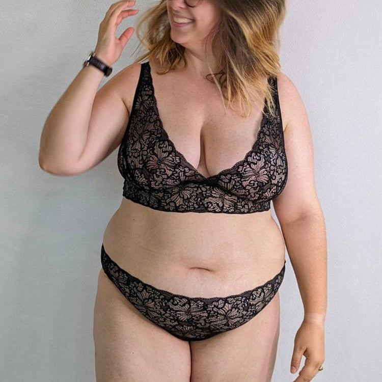 Une femme à lunettes balance ses cheveux et sourit joyeusement.