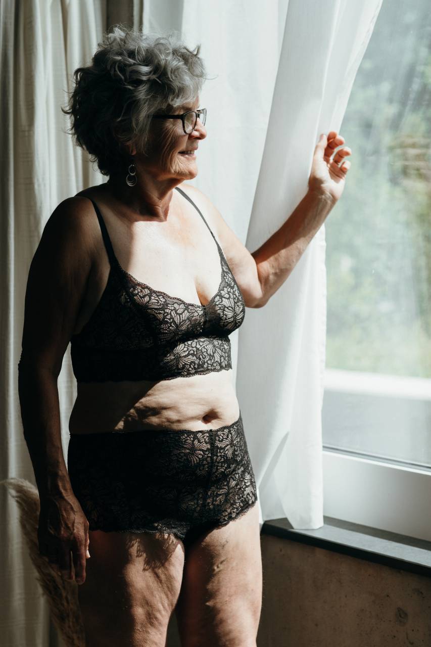 Modèle en ensemble noir en dentelle recyclée regardant par la fenêtre.