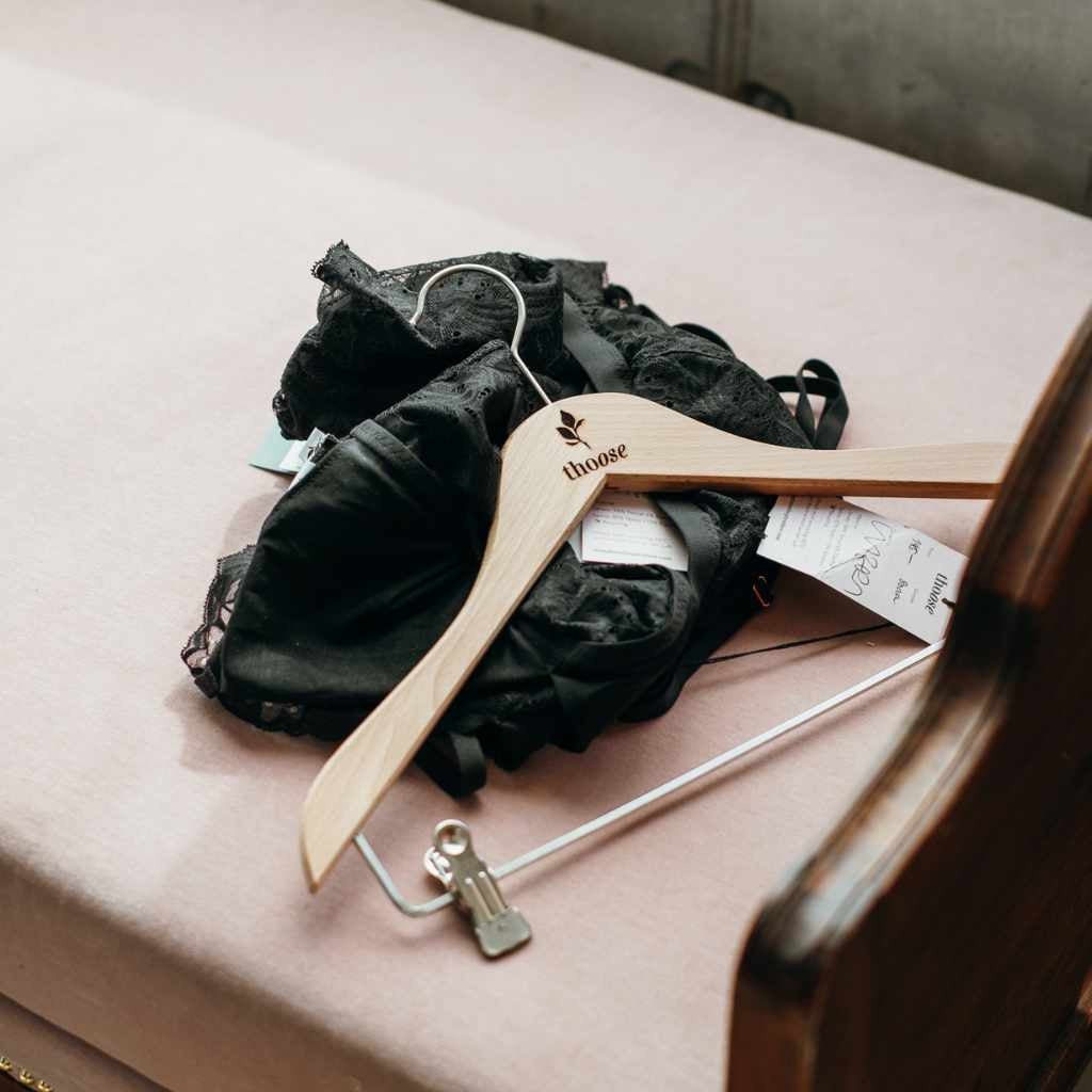 Des vêtements noirs et un cintre sont posés sur un canapé rose.