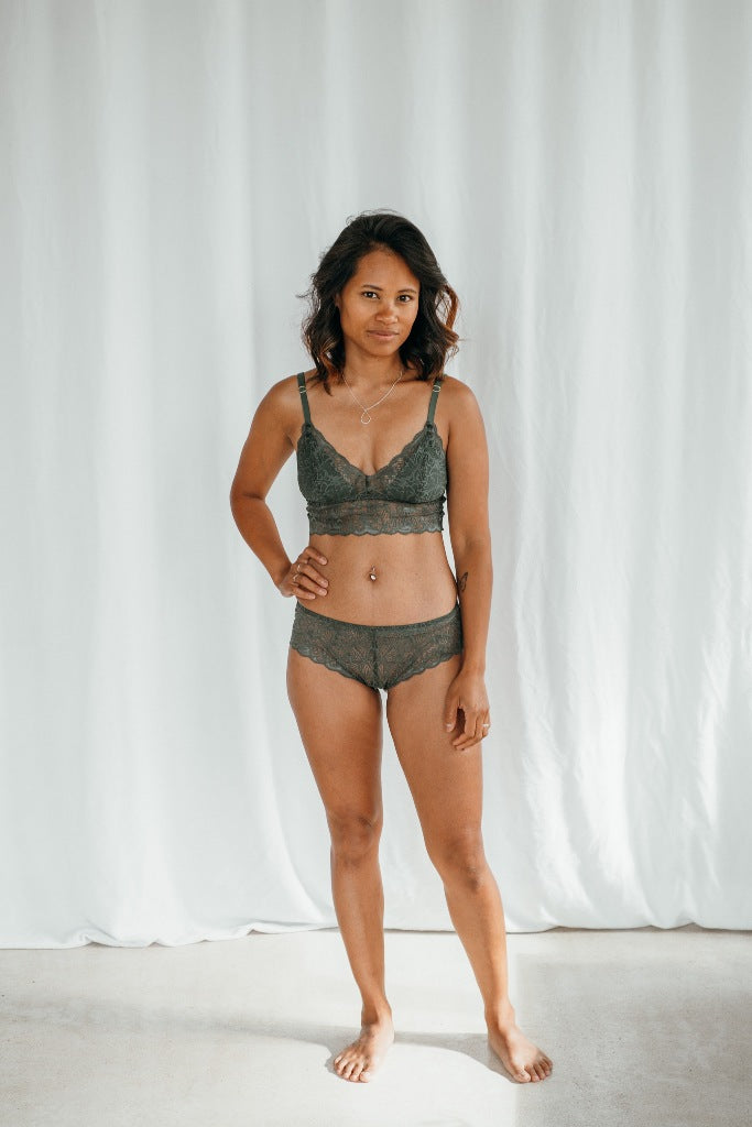 Le modèle porte Vivi Bralette avec des coussinets amovibles et Slip assorti en vert foncé dentelle.
