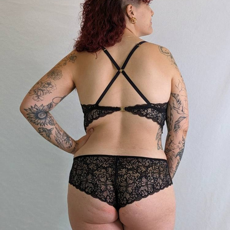 Modèle avec tatouages porte un ensemble de lingerie ludique en fine dentelle.