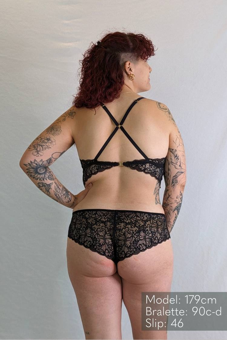 Modèle avec tatouages porte un ensemble de lingerie ludique en fine dentelle.