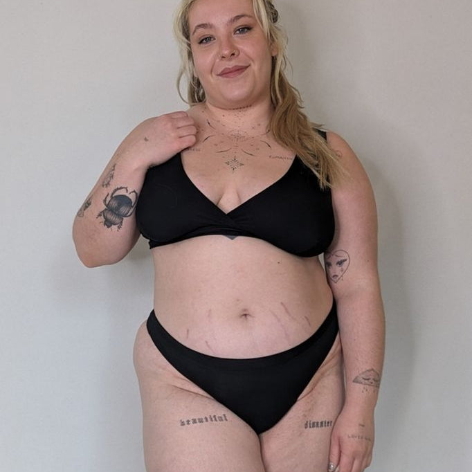 Donna in piedi di fronte alla telecamera e presenta una bella lingerie nera in jersey sostenibile