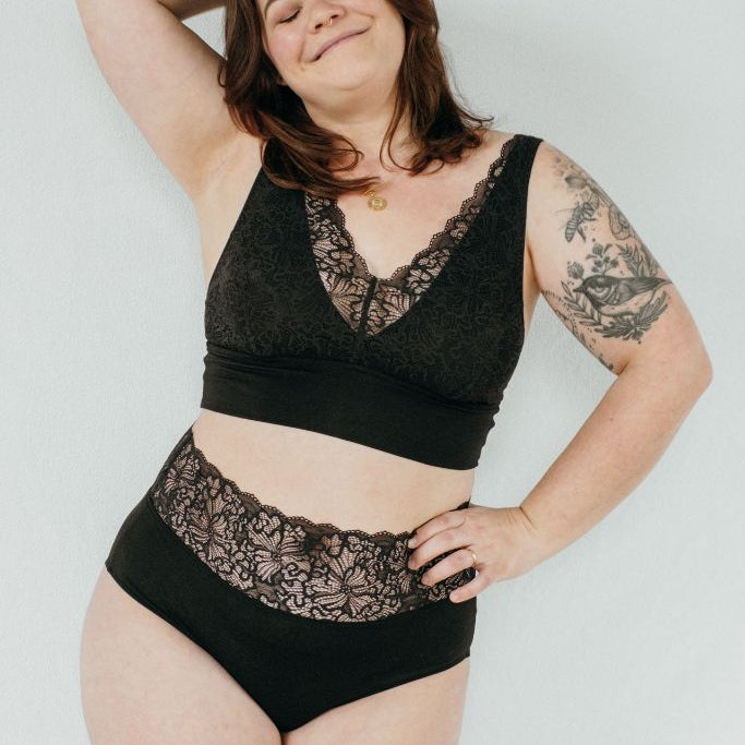 Femme qui rit porte de la belle lingerie noire en tissu durable et doux pour la peau, qui met en valeur les courbes féminines.