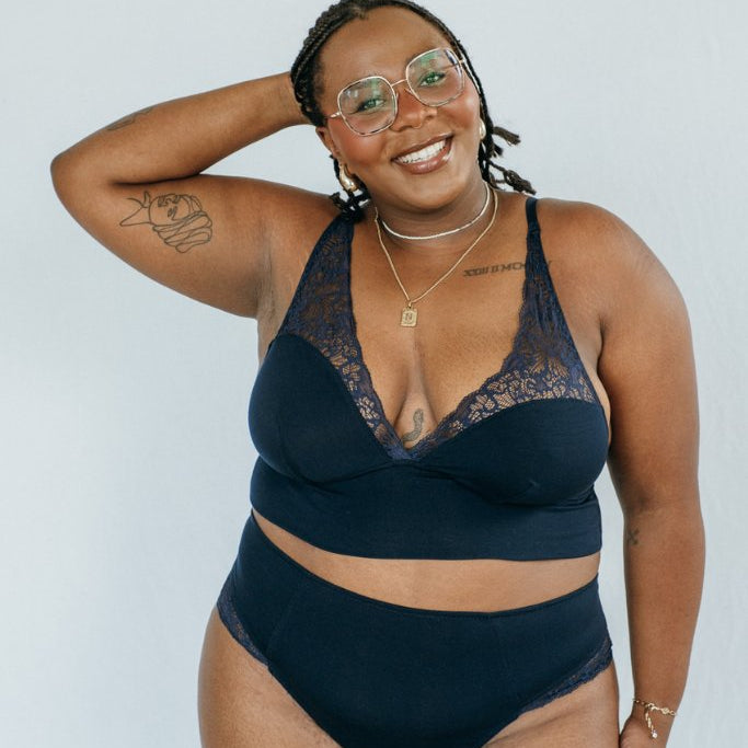 das lachende Model präsentiert sich im dunkel blauen Büstenhalter und dem brazilian Slip