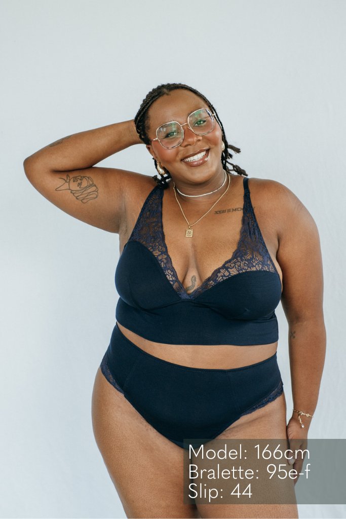 das lachende Model präsentiert sich im dunkel blauen Büstenhalter und dem brazilian Slip