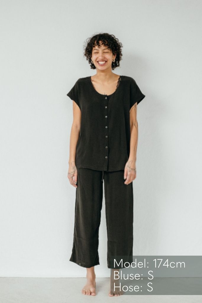 la femme aux cheveux bouclés porte le haut Noe et le pantalon Coco en cupro et viscose durables