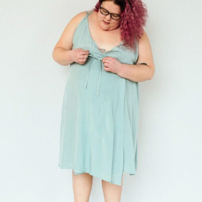 La femme est en train de nouer les lacets de la robe de Zia sur le devant.