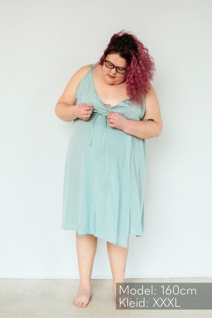 La femme est en train de nouer les lacets de la robe de Zia sur le devant.