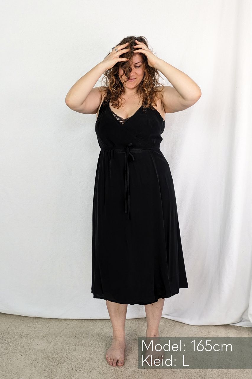 Le modèle pose devant l'appareil photo et porte la belle robe-slip Zia en noir