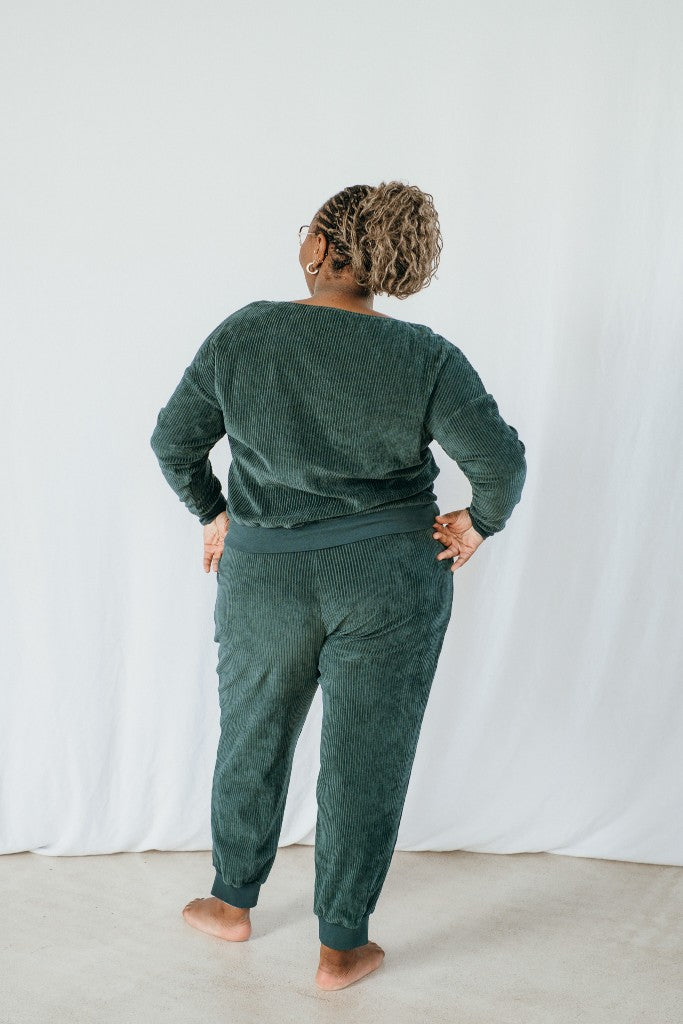 Model trägt Pyjama in jadegrünem Cord, den Rücken hat sie der Kamera zugewandt.