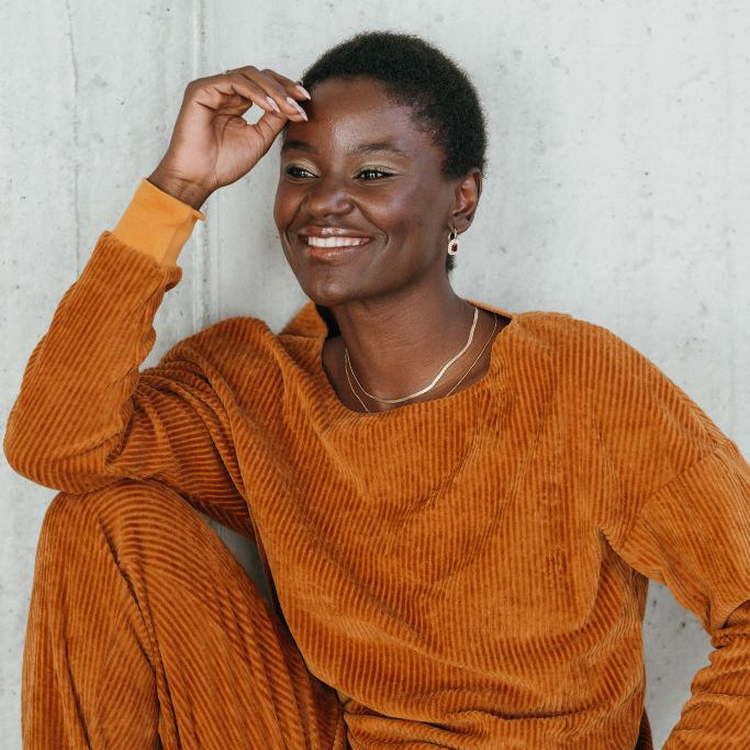 Portraitbild vom Model mit dem Chloé Pullover in Ocker. Sie blickt verträumt neben der Kamera vorbei.