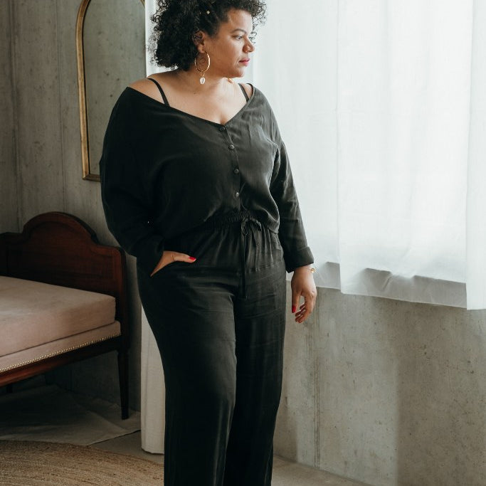 Une femme porte un pyjama en soie végétalienne et se tient devant la fenêtre.