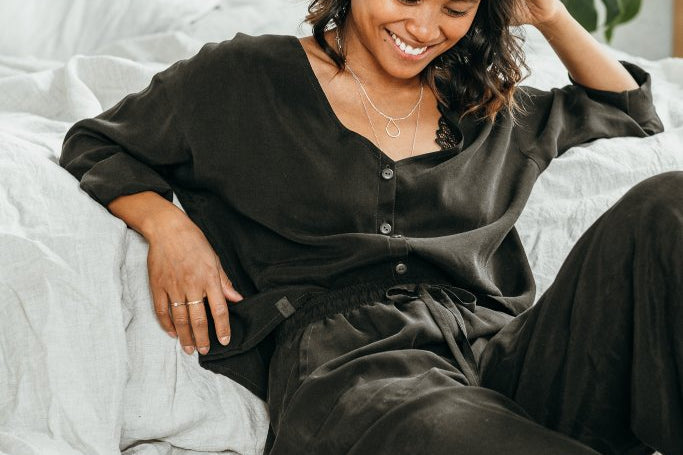 Une femme porte un pyjama noir et sourit