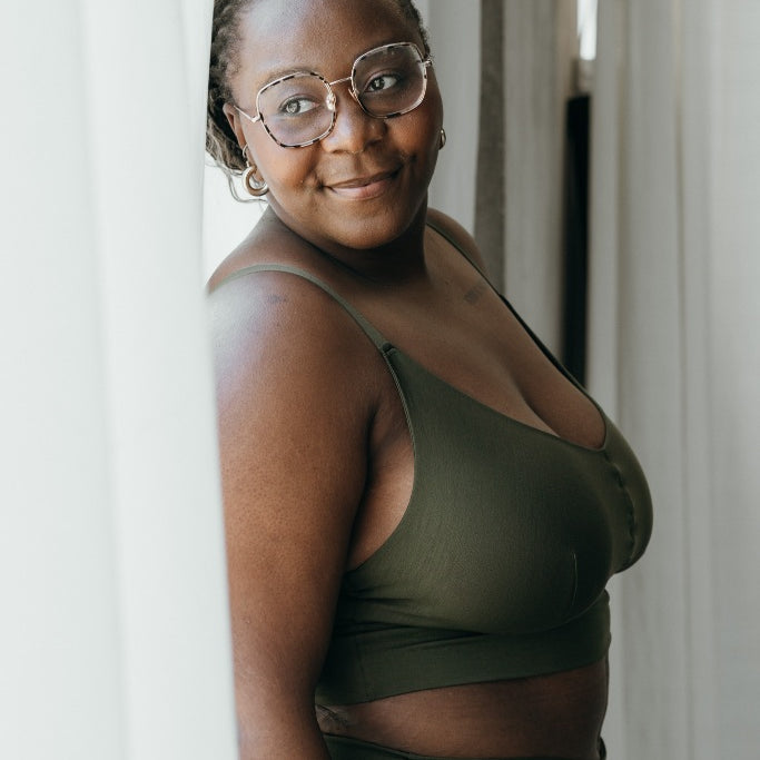 Moodbild, auf dem das Model das Emma Set in Olive trägt und gegen das Fenster lehnt