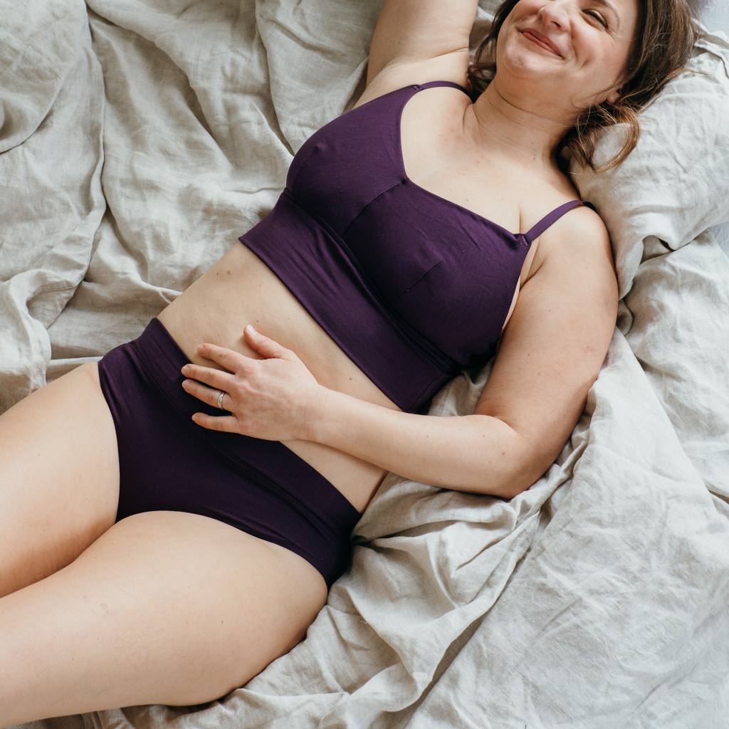 Moodbild von Emma in Ultraviolet. Model liegt auf dem Rücken und lächelt in die Kamera.