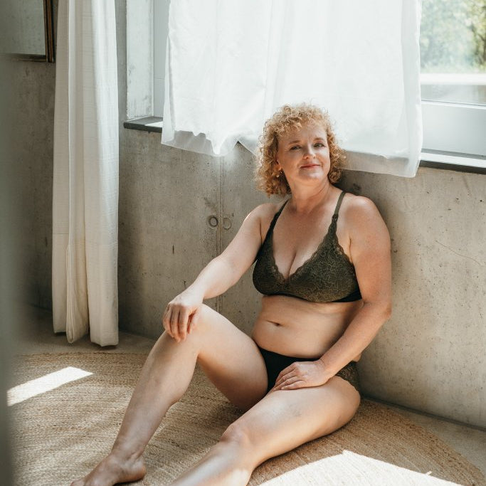 Model sitzt am Boden und trägt das Gisele Set. Den Rücken hat sie an der Wand angelehnt.