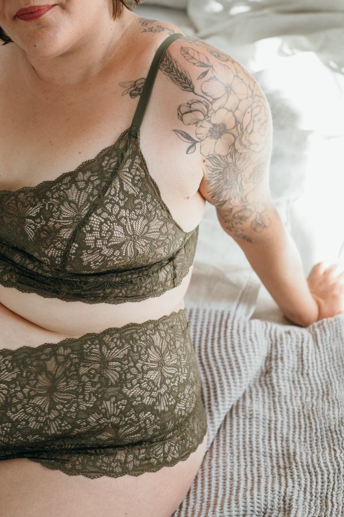 Model trägt Joy Set in der Farbe Olive. Sie sitzt auf dem Bett.