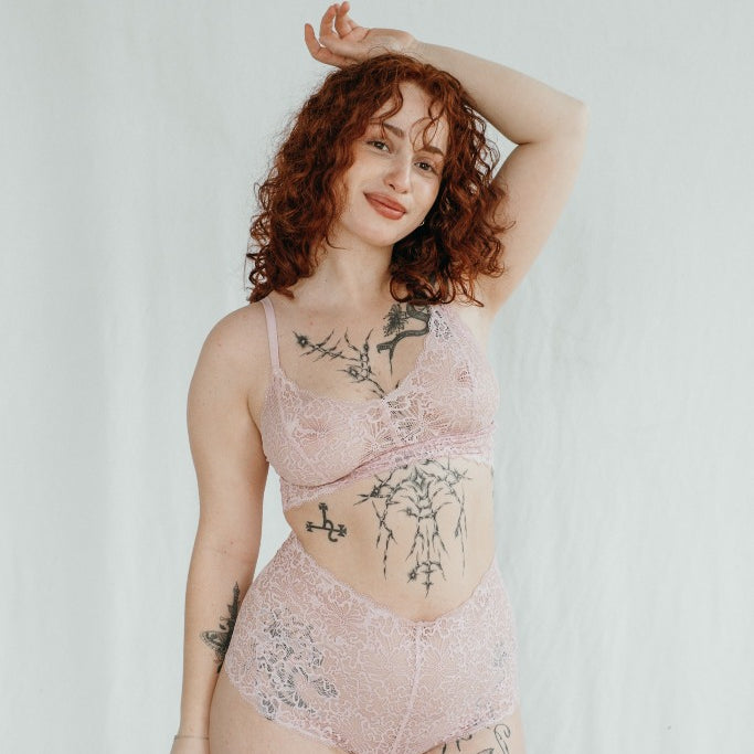 le modèle tient son bras au-dessus de sa tête et pose dans un joli Bralette et Slip en dentelle très fine