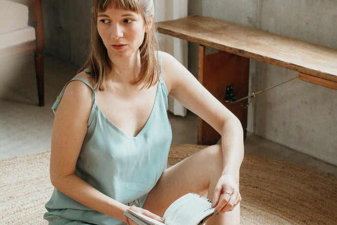 La femme tient un livre à la main et se montre en Kat Top de couleur summer mint