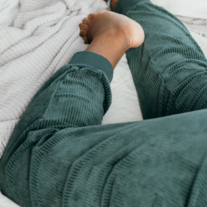 Detailaufnahme von der Kelly Hose in Jadegrün. Model liegt bauchlinks auf dem Bett.