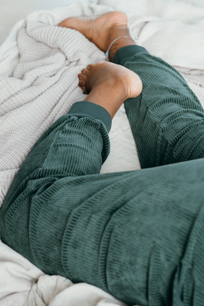 Detailaufnahme von der Kelly Hose in Jadegrün. Model liegt bauchlinks auf dem Bett.