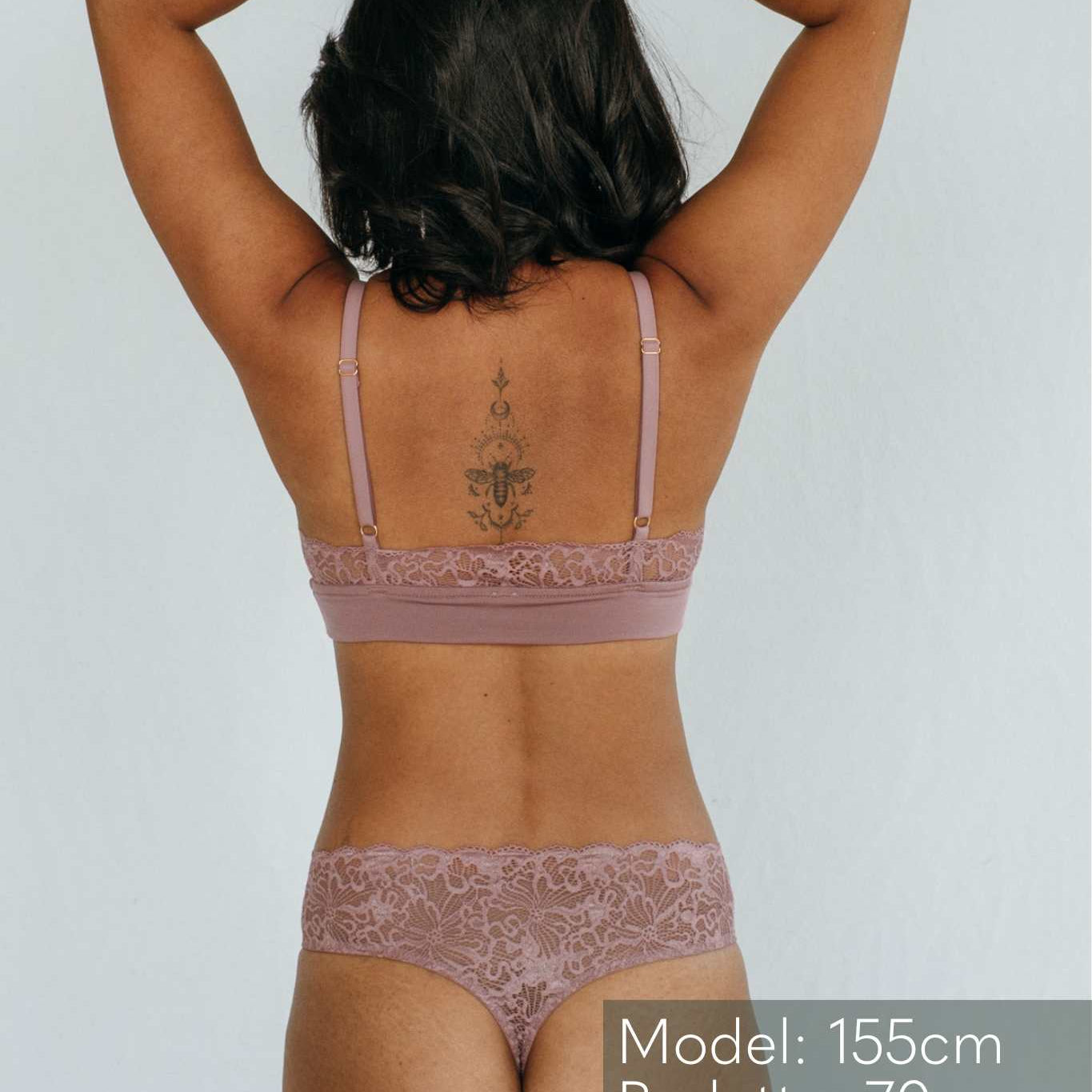 das Model zeigt sich von hinten in einem Spitzen String und einem Bralette mit verstellbaren Trägern