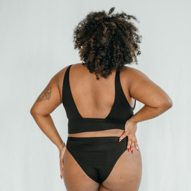 Le modèle se montre de dos et présente l'ensemble de sous-vêtements Leila en noir