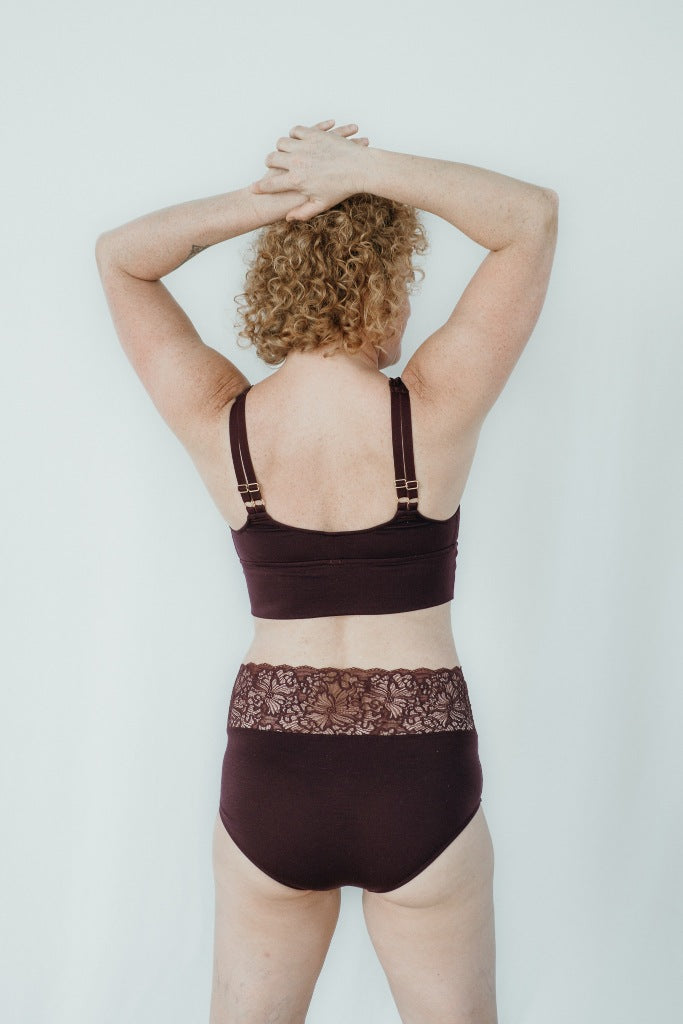 Model trägt das Nelly Set in der Farbe Aubergine, den Rücken hat sie der Kamera zugewandt.