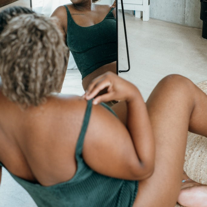 Detailaufnahme vom jadegrünen Ronja Body. Model sitzt vor dem Spiegel.