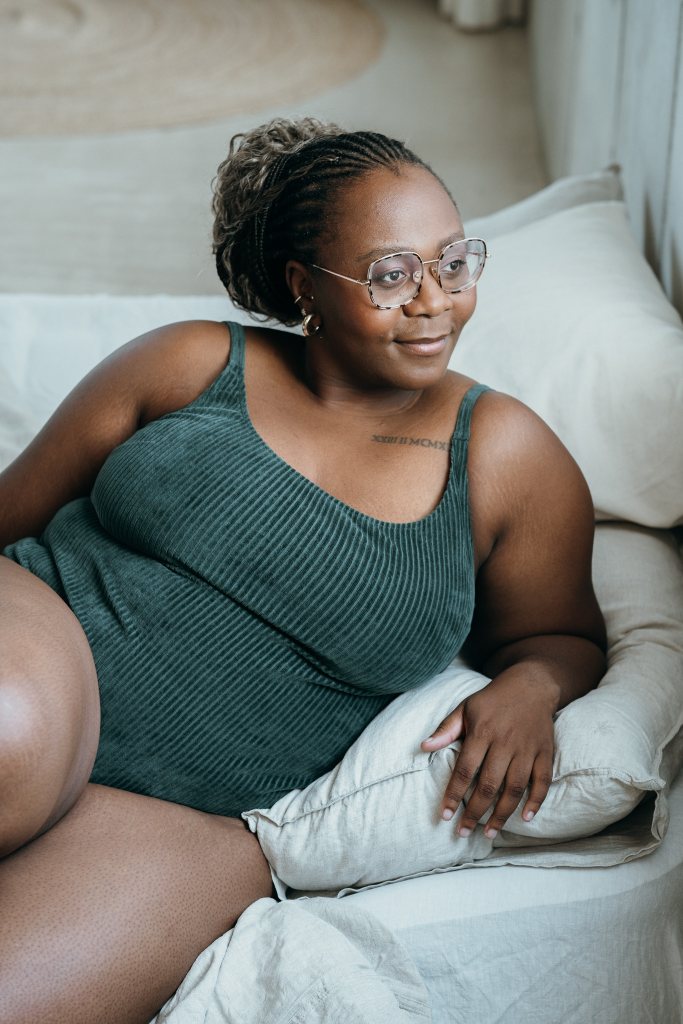 Model trägt jadegrünes Ronja Body und liegt seitwärts auf dem Bett.