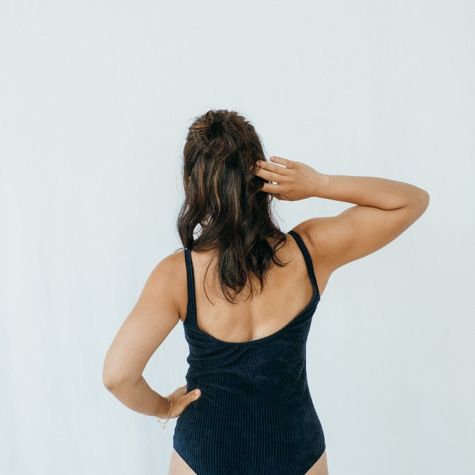 Model trägt Ronja Body in Dunkelblauem Cord, ihr Rücken ist der Kamera zugewandt.