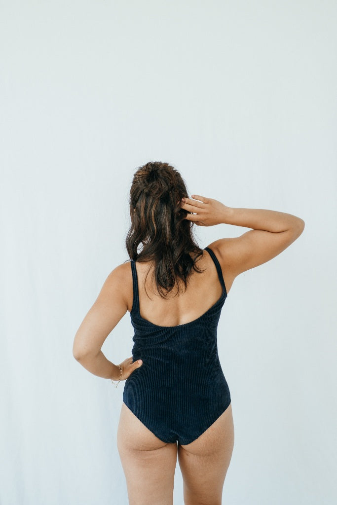 Model trägt Ronja Body in Dunkelblauem Cord, ihr Rücken ist der Kamera zugewandt.