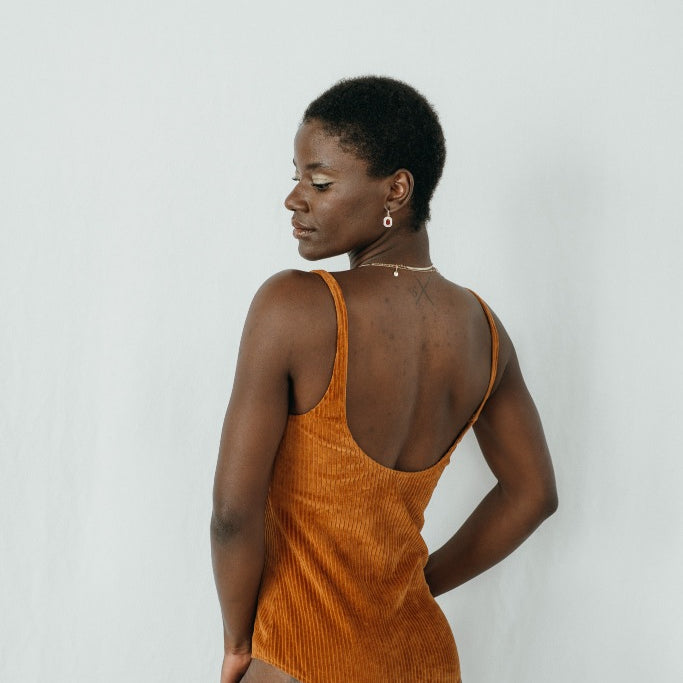 Model trägt das Ronja Body in ockerfarbigem Cord, ihr Rücken ist der Kamera zugewandt.