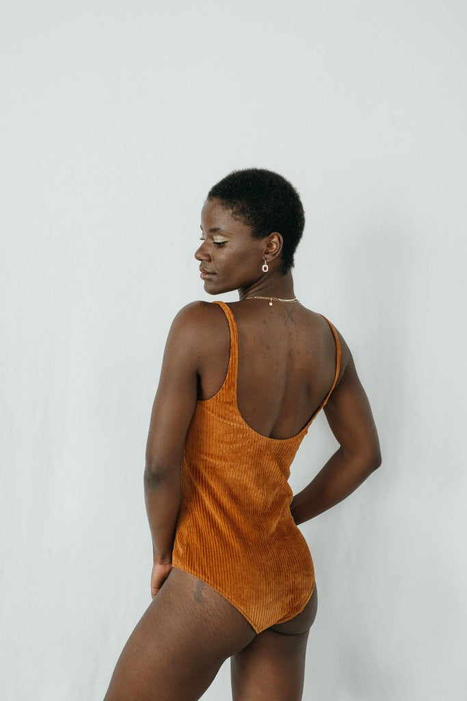 Model trägt das Ronja Body in ockerfarbigem Cord, ihr Rücken ist der Kamera zugewandt.