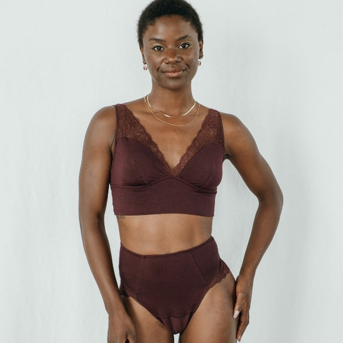 Model trägt das Sophie Set in der Farbe Aubergine. Sie blickt in die Kamera und lächelt.