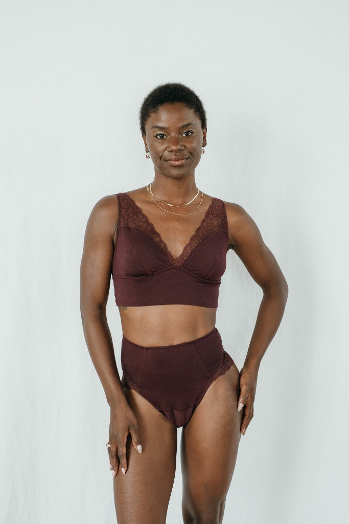 Model trägt das Sophie Set in der Farbe Aubergine. Sie blickt in die Kamera und lächelt.