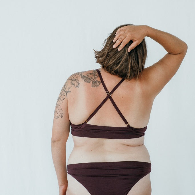 Model trägt das Thea Set in der Farbe Aubergine, den Rücken hat sie der Kamera zugewandt.