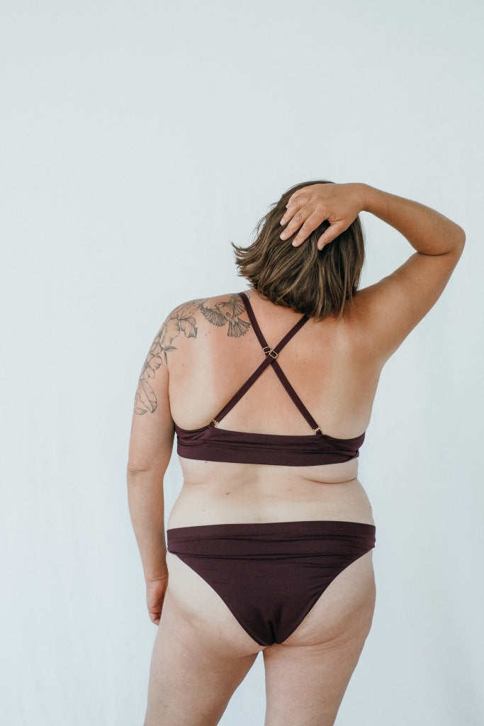 Model trägt das Thea Set in der Farbe Aubergine, den Rücken hat sie der Kamera zugewandt.