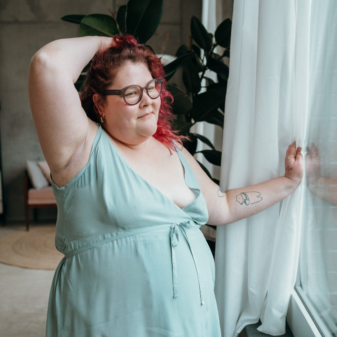 le mannequin aux cheveux roux pose à la fenêtre vêtu de la robe Zia