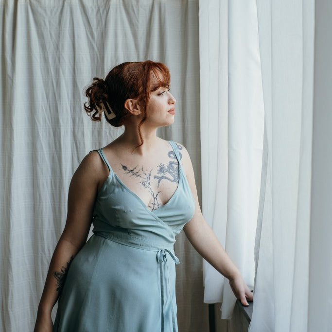 Model trägt das Zia Slipdress in der Farbe Summer Mint. Sie blickt zum Fenster hinaus.
