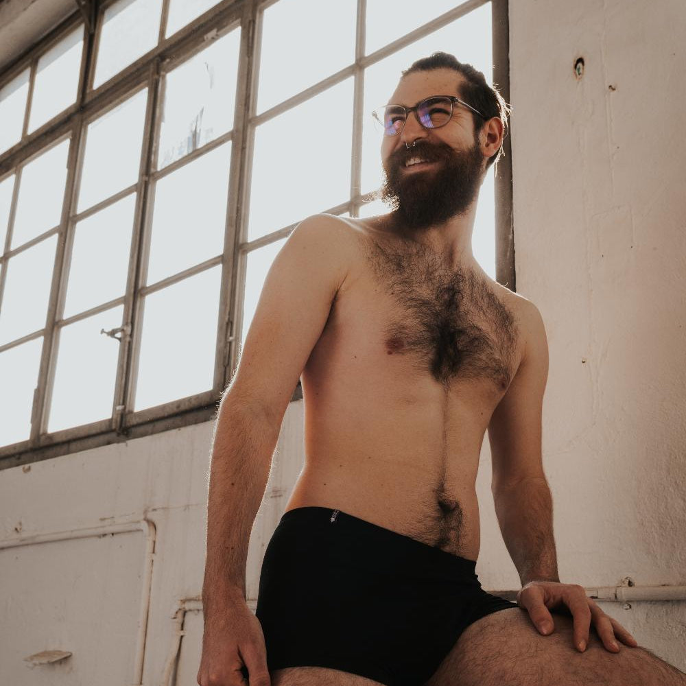 Personne assise sur une caisse. Elle porte un caleçon en TENCEL™ noir.