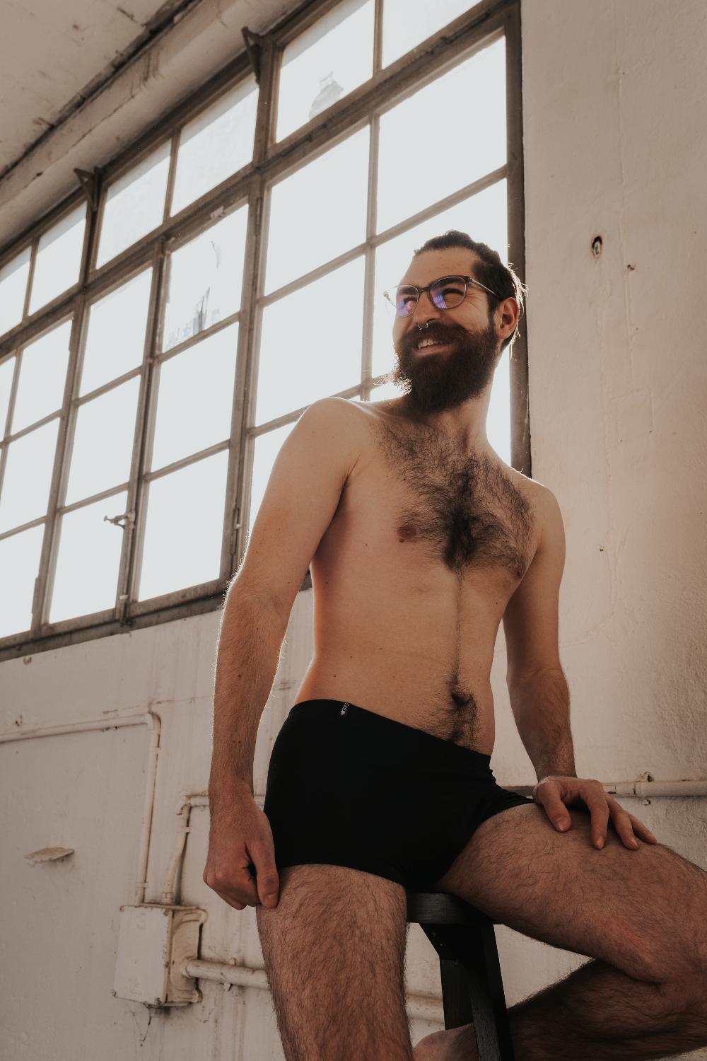 Personne assise sur une caisse. Elle porte un caleçon en TENCEL™ noir.