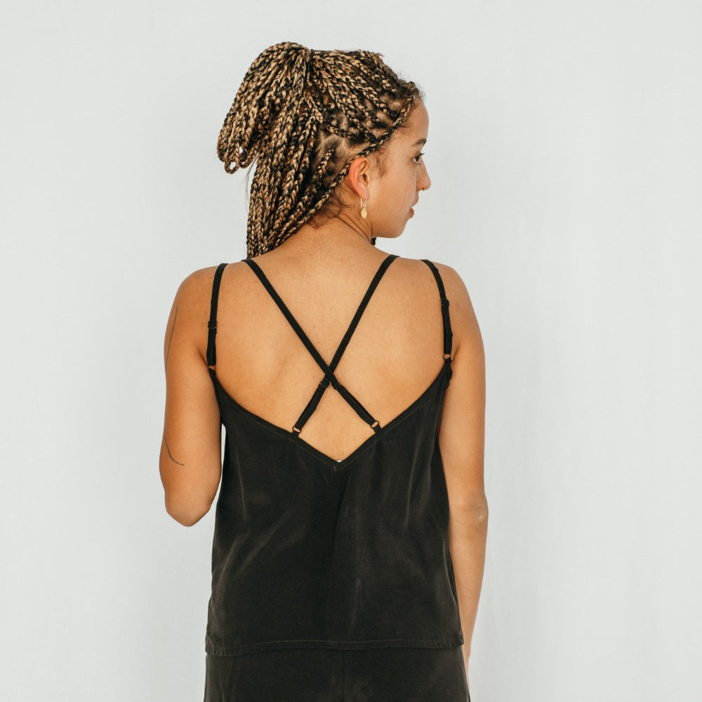 La femme porte un short et un haut à bretelles croisées en cupro soyeux.