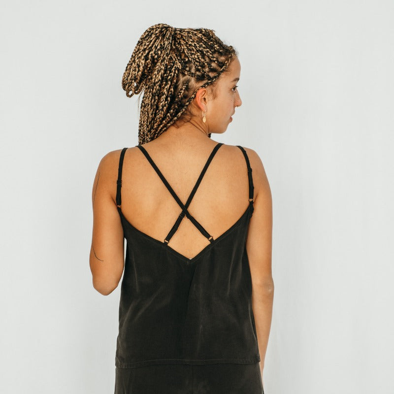 Le modèle porte un top avec des bretelles croisées et un short aéré en noir.